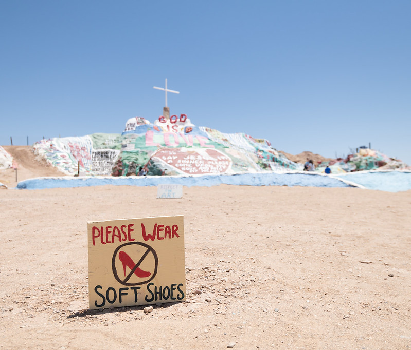 A sign in front of the Salvation Mountain, a painted sand monument to God, asking visitors to wear soft shoes
